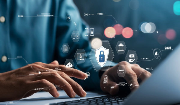 Person typing on a laptop with a digital overlay of a shield, padlock and data security icons.