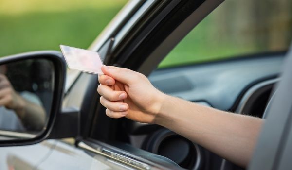 Person holding an identification card out of an open car window.