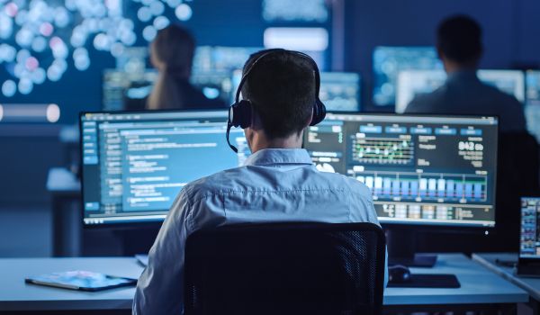 Male Data Scientist Works on Personal Computer in Big Infrastructure Control and Monitoring Room