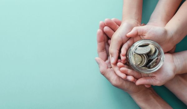 child and adult holding money jar