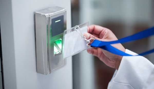 Employee presenting an identification badge to a workplace access-control reader.