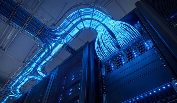 Low angle view of glowing blue network cables running through server racks in a high-tech data center