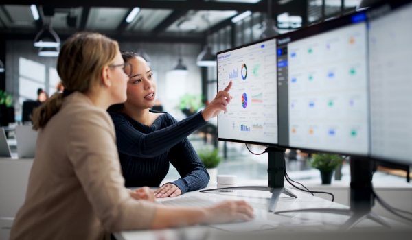 A group of four professionals—including construction engineers in safety vests and office executives—gathered around a table in a modern glass conference room for a meeting.