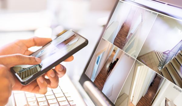 Person watching camera feeds on smartphone and laptop