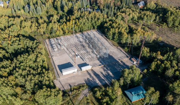 Aerial view of an electrical substation surrounded by a dense forest.