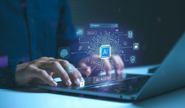 Person typing on a laptop with an overlaid AI agent graphic showing a digital chip, connected icons and security symbols.