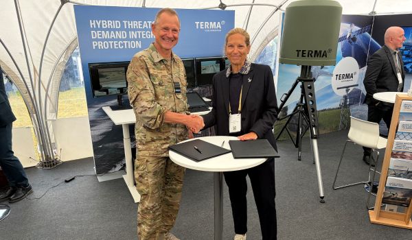 two people shaking hands and smiling at camera