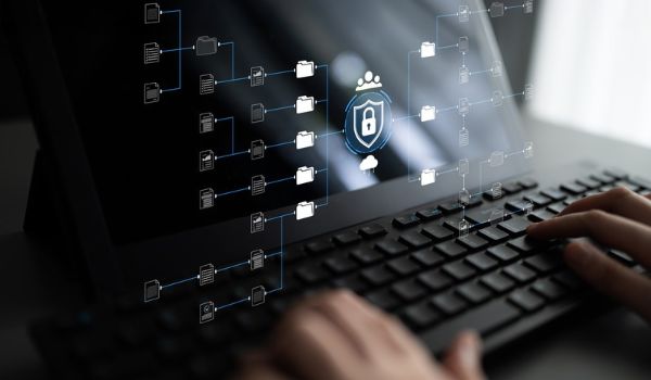Hands typing on a laptop with a digital overlay of connected files and a padlock symbol representing data security.