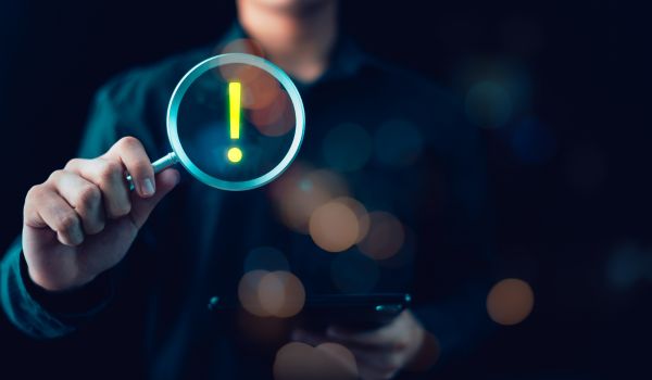 Cybersecurity analyst investigates digital risk alerts using magnifying glass inspection