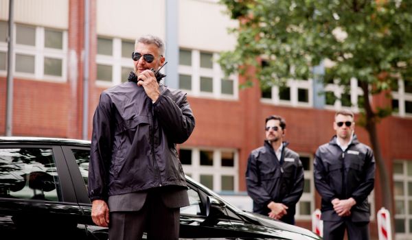 Security personnel surrounding black vehicle