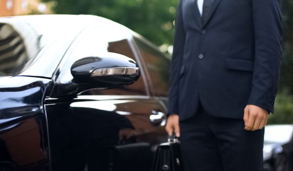 Premium class driver standing near luxury car