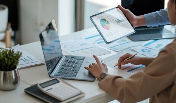 Office workers reviewing analytics on laptop and tablet