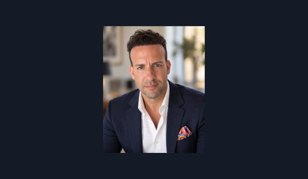 Headshot of Richie Perna, Chief Revenue Officer, wearing a navy blue blazer, an open-collar white dress shirt, and a colorful pocket square.