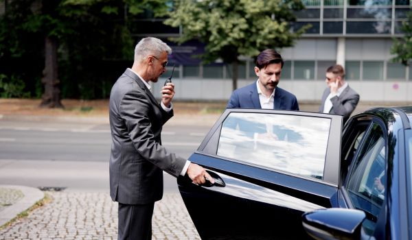 Executive with security opening a car door
