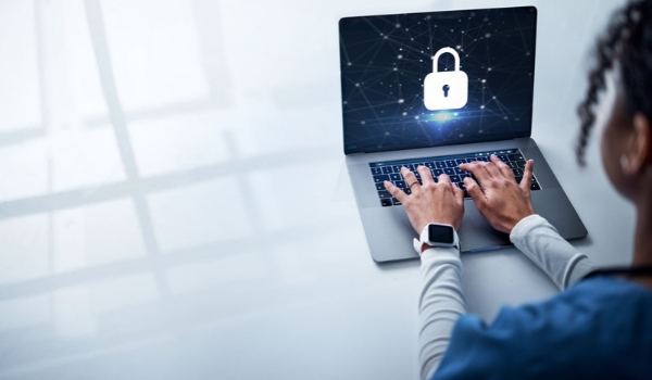 A person types on a laptop displaying a digital padlock icon on the screen, symbolizing cybersecurity.