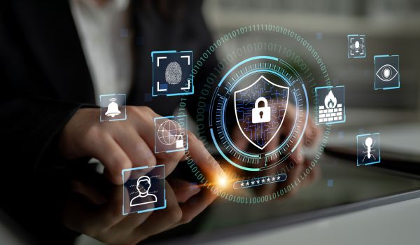 Person using a tablet with a digital cybersecurity interface displaying a locked shield, fingerprint scanner and identity verification icons.
