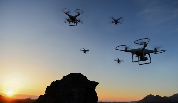 Drones flying over rocks at sunset