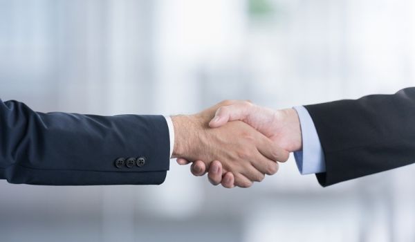 Two men in business attire shaking hands.