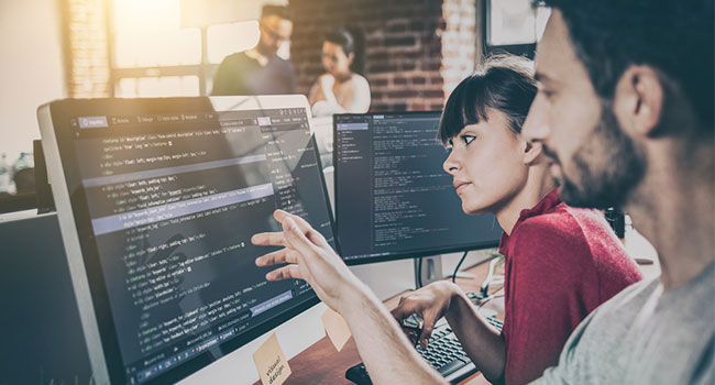 Two people using computer in office space